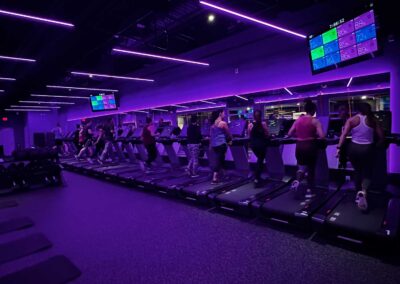 Members on treadmills in purple color therapy